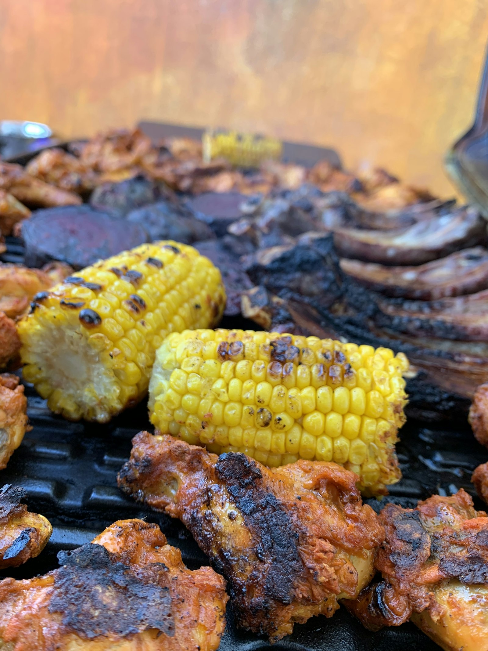 Pollo y elotes asándose sobre una parrilla de carbón